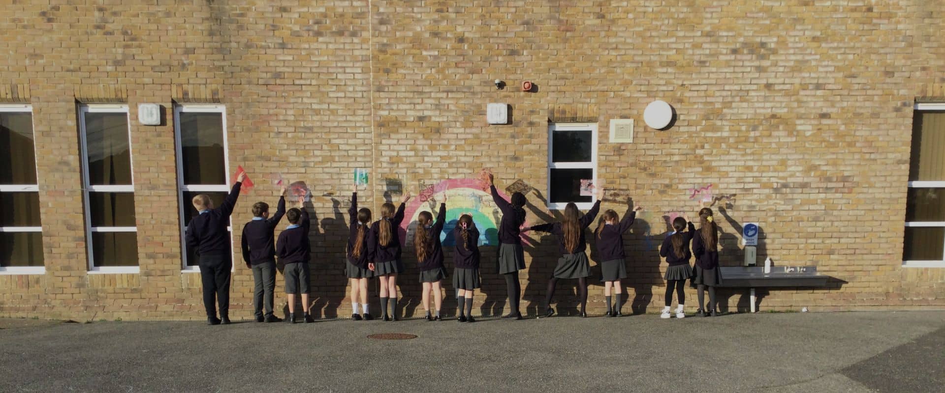 A group of school children creating shadow art on their school wall as part of Kathy Williams artist visit to Hunnyhill Primary.