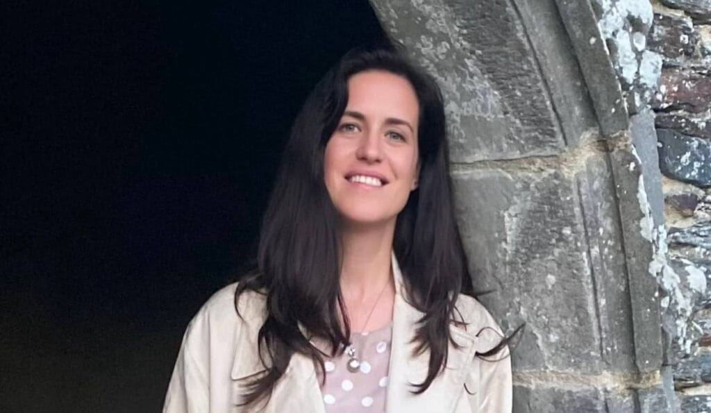 An image of Jo Ridley, she smiles inside a castle's archway.