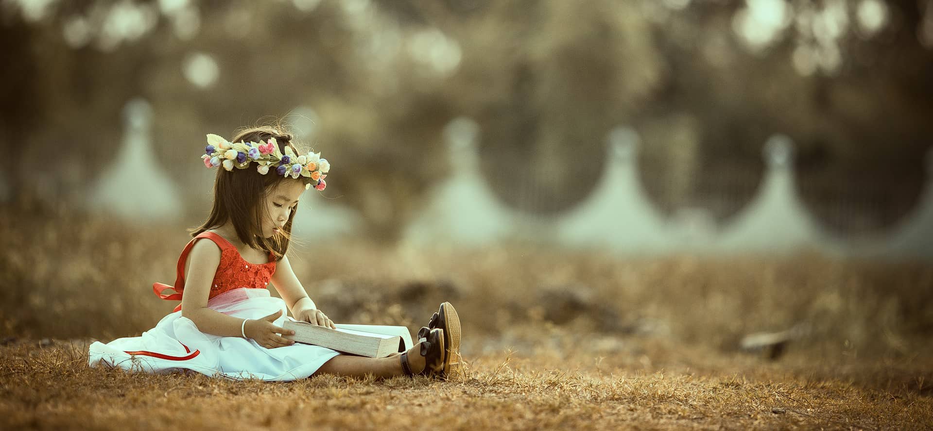 Child sat on the grass reading a book