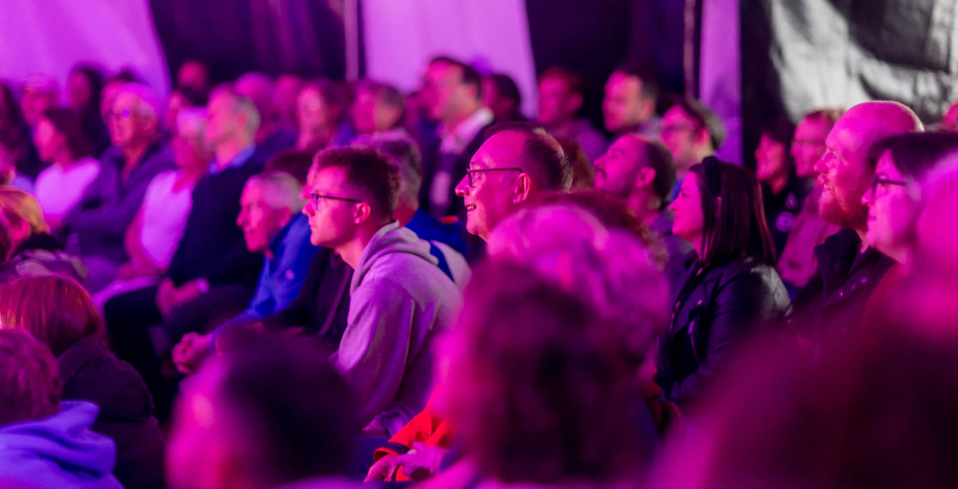 Purple light on the audience watching show in Magpie Tent