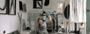 Artist, Laura Hathaway is painting a straight, black, thick line on glass