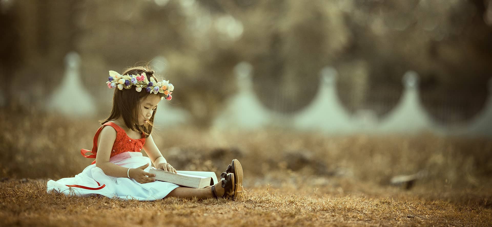 Child sat on the grass reading a book