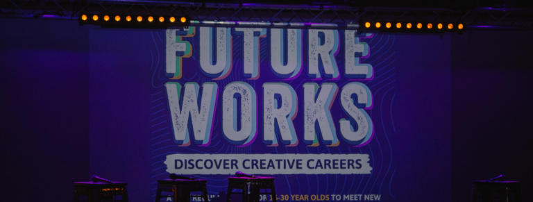 A photo of a projected screen that says 'Future Works'. It's the background of the stage where the speakers would sit.