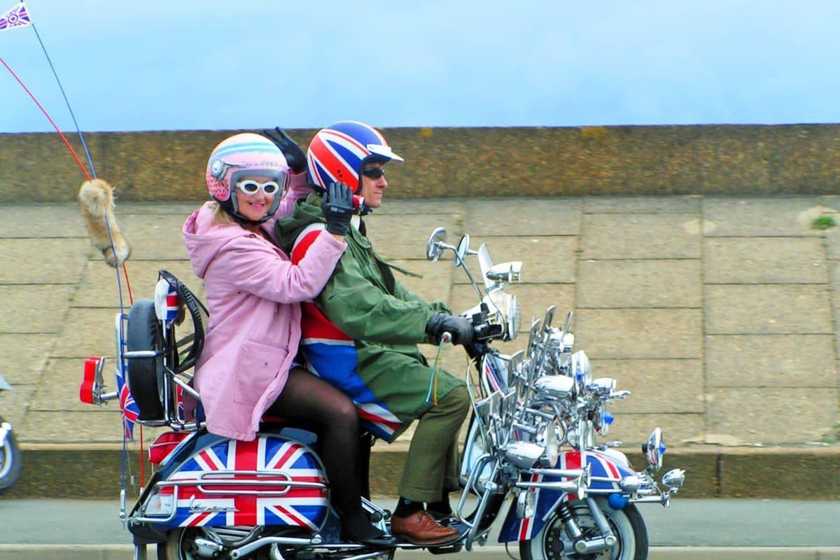 Woman and man riding along the seafront on a scooter