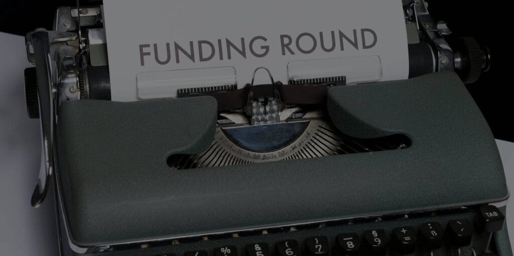Typewriter with sheet of typed writing saying Funding Round