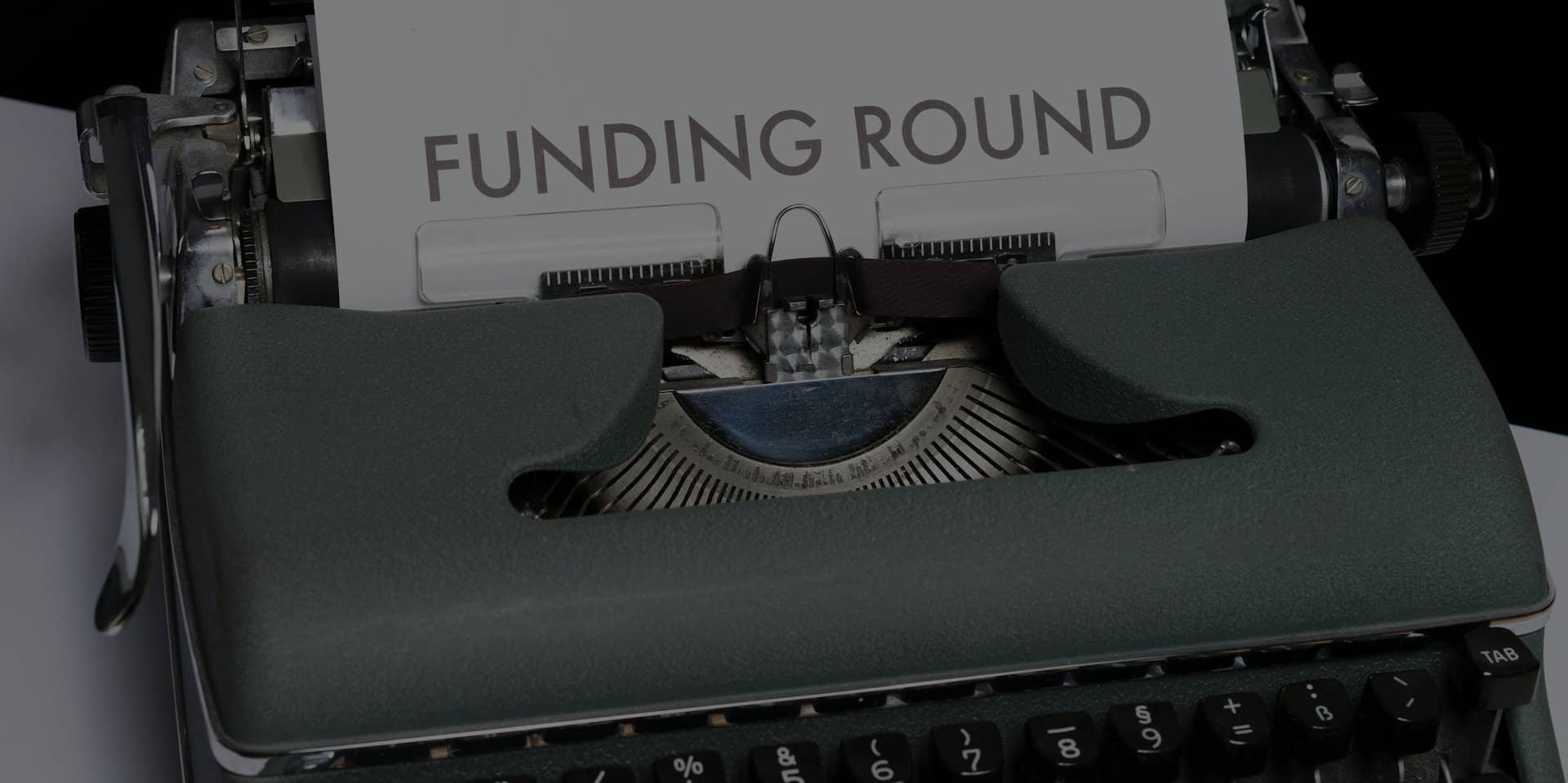 Typewriter with sheet of typed writing saying Funding Round