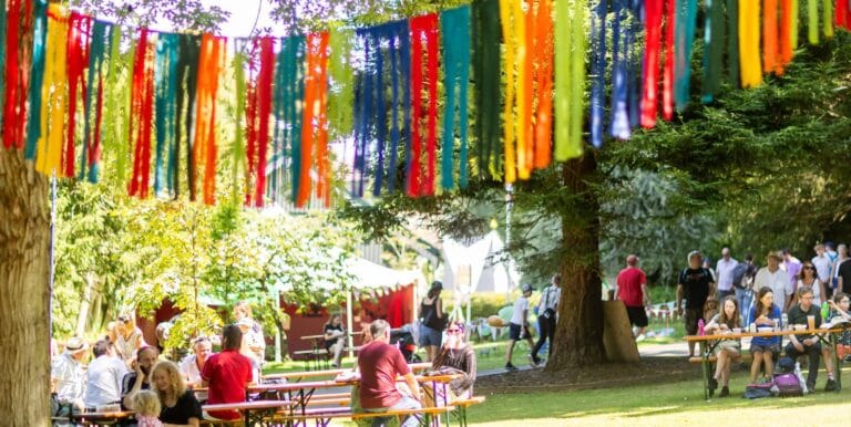 Fringe bunting at Ventnor Fringe Festival - hanging above people on benches in the park