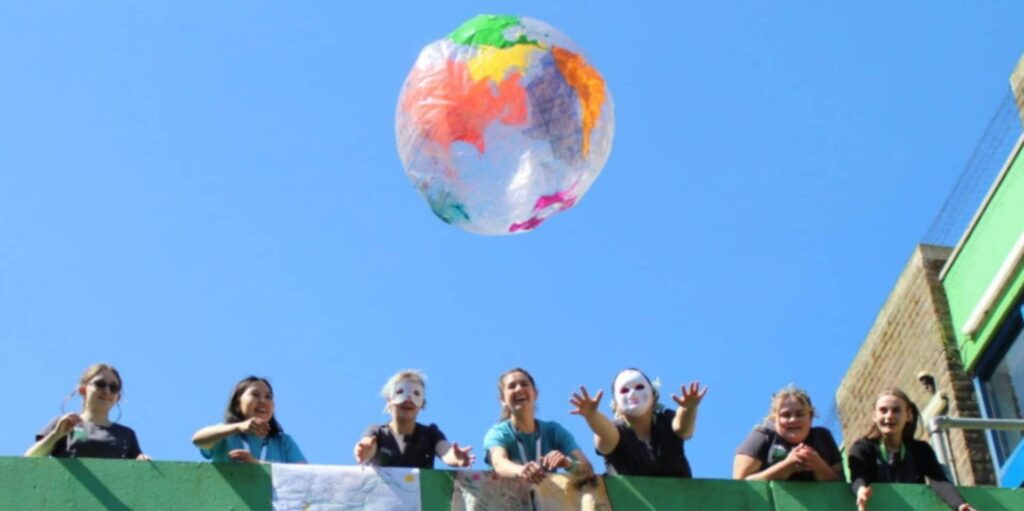 Globe balloon in the air with people looking at it from a balcony