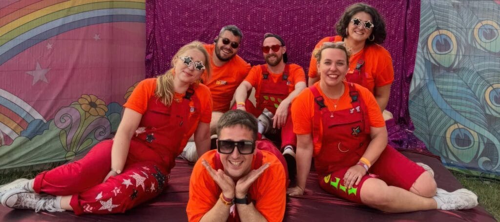 Horsebox Theatre Group members dressed in red jumpsuits and posing for the camera