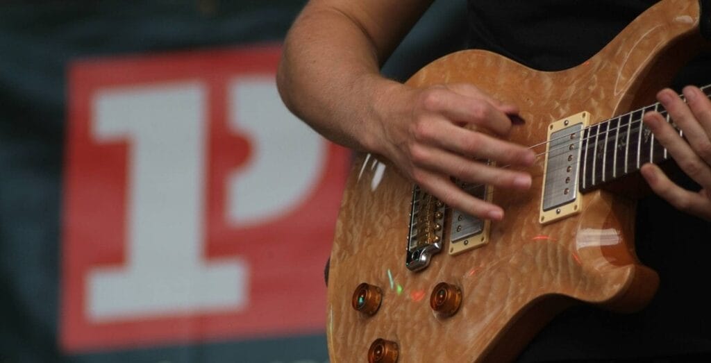 Teenage musician playing guitar with Platform One logo in background