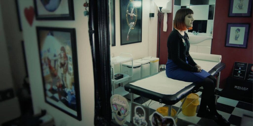 Sarah Murphy sat in Pin Up Girls Boutique. The floors are a chequerboard and the walls are a deep red colour.