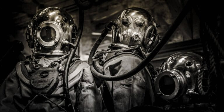 Black and white photo of Three vintage diving suits