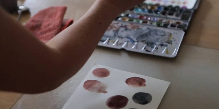 Artist painting circles of colour on cartridge paper