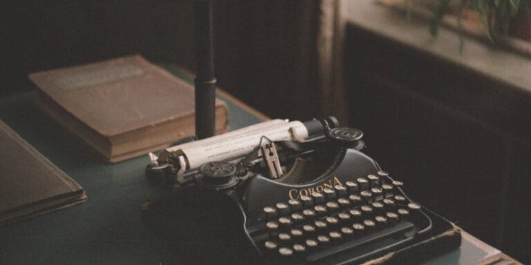 dark scene showing corona typewriter on desk with old worn books