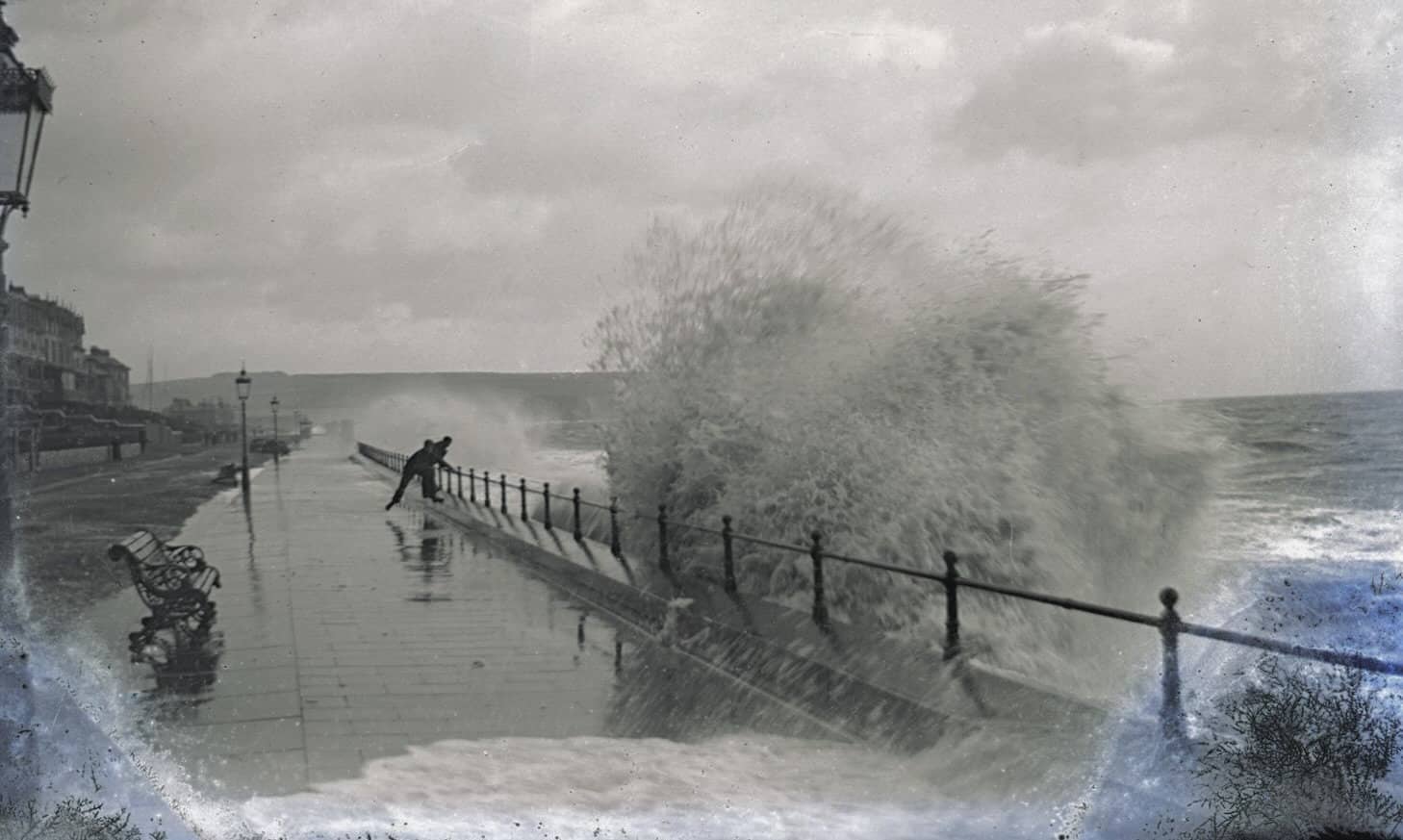 Damaged negative capturing a dramatic high tide in the Bay with someone walking close to the railings and being covered in waves