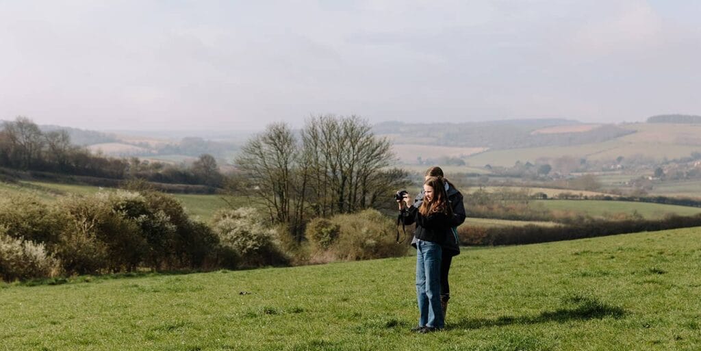 Young people in a field taking photographs