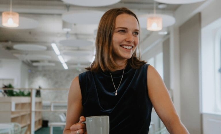 Ella Clapham from Isle of Wight Council's Regeneration team joins Creative Island's Board of Trustees. She's smiling with a cup of tea, and wearing a navy blue dress.