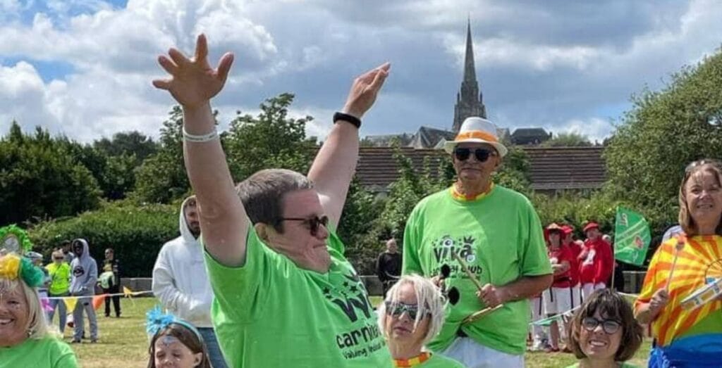 Viva Carnival members with drums in Ryde. A young lad at the front is dancing with his arms up in the sky!