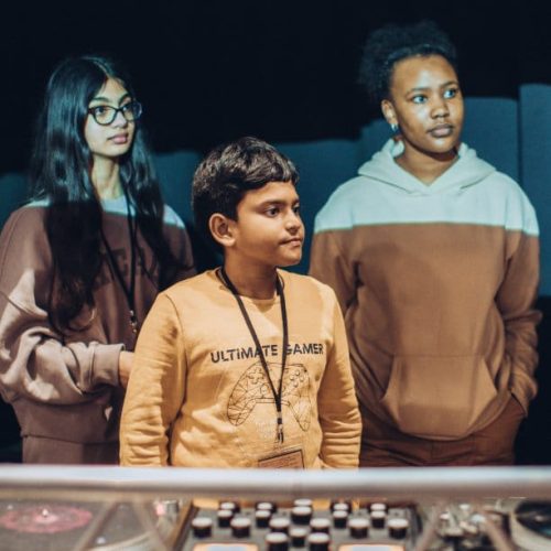 Three children standing in front of a sound desk