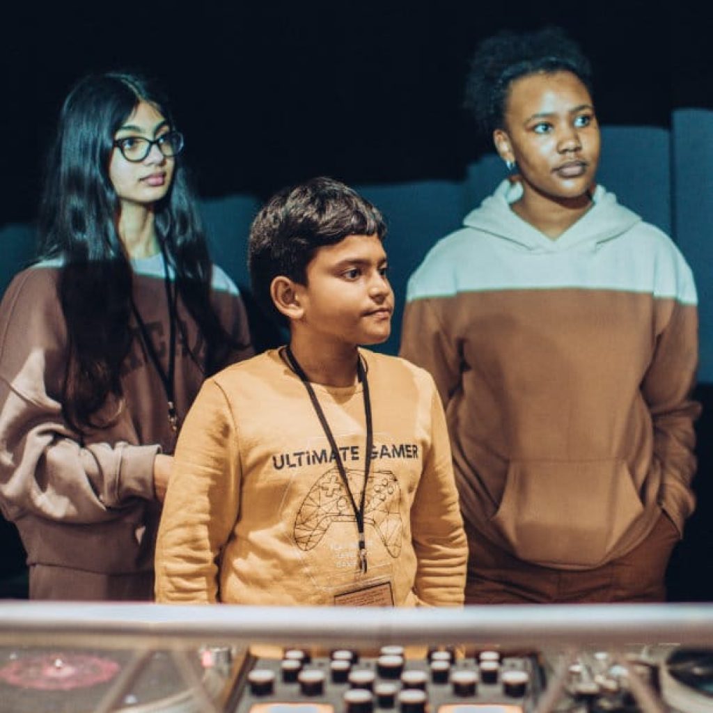 Three children standing in front of a sound desk