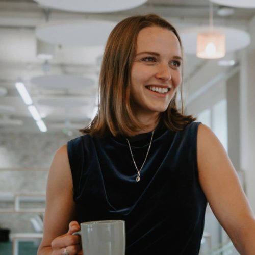 Ella Clapham from Isle of Wight Council's Regeneration team joins Creative Island's Board of Trustees. She's smiling with a cup of tea, and wearing a navy blue dress.