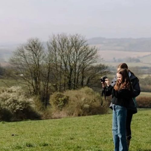 Young person being shown how to take landscape photo by Maria Bell Photography